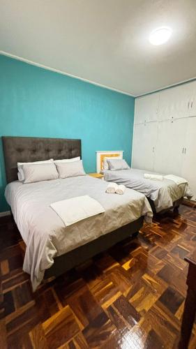 two beds in a bedroom with blue walls and wooden floors at One Thirty Six in Gqeberha