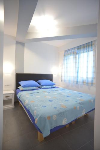 een slaapkamer met een bed met blauwe lakens en blauwe kussens bij Apartment Hermes in Belgrado