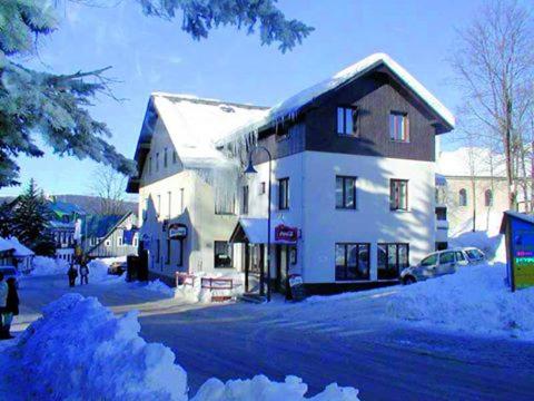 a large white building with snow on the ground at Hotel Anna in Harrachov