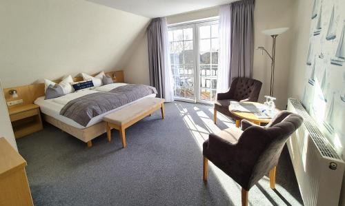 a bedroom with a bed and a table and chairs at Hotel Schiffer in Bensersiel