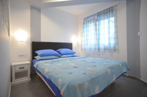 Un dormitorio con una cama con almohadas azules y una ventana en Apartment Hermes, en Belgrado