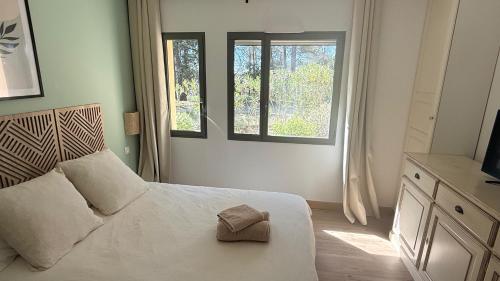 a bedroom with a white bed with two windows at Appartement golf saumane Celomidie in Saumane-de-Vaucluse
