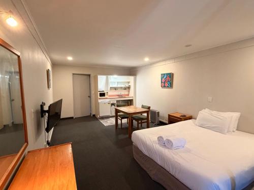 a hotel room with a bed and a table at Karaka Tree Motel in Taupo