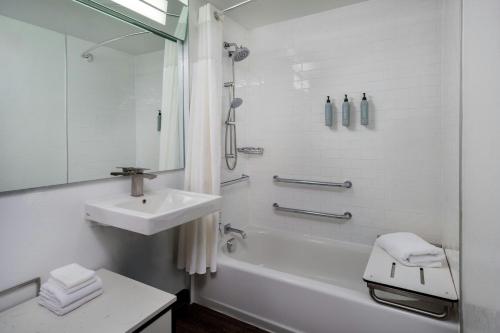 a white bathroom with a sink and a bath tub at Courtyard Miami Beach South Beach in Miami Beach