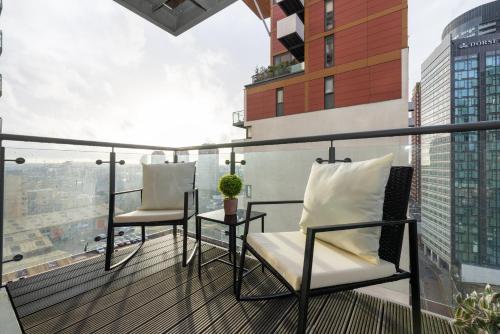 a balcony with two chairs on top of a building at Cosy, modern high rise with views! 2 bedroom in London