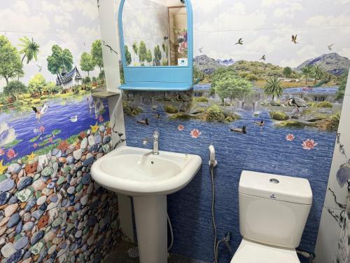 a bathroom with a toilet and a sink with a mural at Beliya Rock View in Dambulla