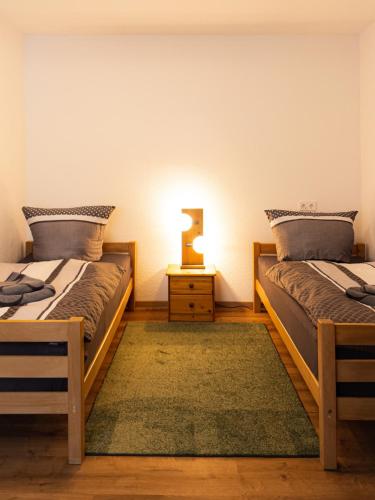 two beds in a room with a night stand and a lamp at EDGE of FOREST in Titisee-Neustadt