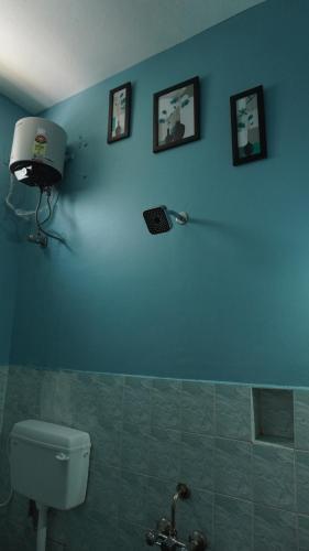 a blue bathroom with a toilet and pictures on the wall at Grey Pearl Homestay in Pondicherry