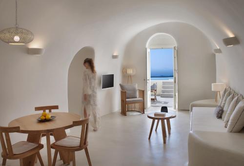a woman walking through a living room with a table at Villa Ioli Anastasia in Firostefani