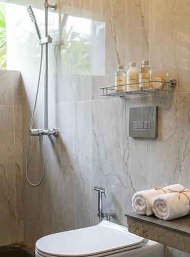 a bathroom with a shower and a toilet and towels at Villa 55 Galle in Galle