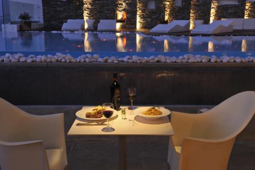 a table with two plates of food and a bottle of wine at Hotel Senia - Onar Hotels Collection in Naousa