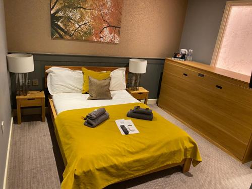 a bedroom with a bed with yellow sheets and two towels at The Tower Arms Hotel in Iver