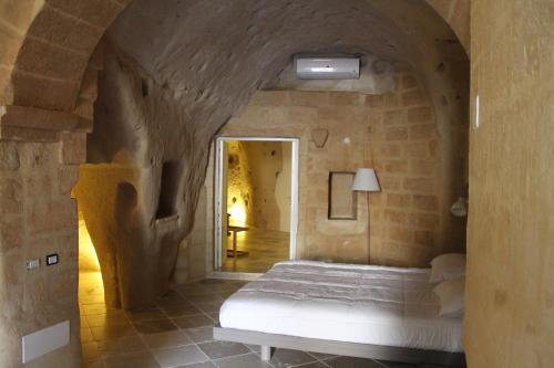 a bedroom with a bed in a stone wall at Antico Convicino Rooms Suites & SPA in Matera