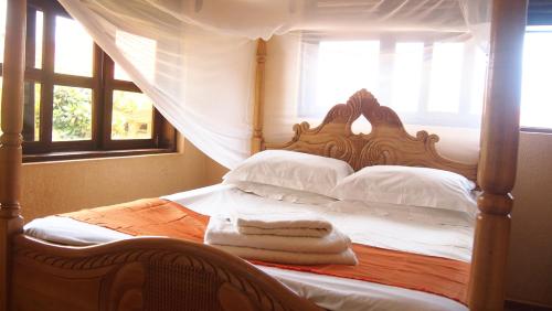 ein Schlafzimmer mit einem Bett mit weißen Kissen und einem Fenster in der Unterkunft Keelan ace villas in Kampala