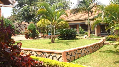 a house with a fence and a yard with palm trees at Keelan ace villas in Kampala