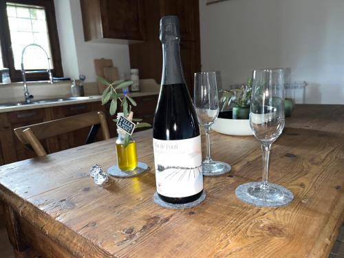 a bottle of wine sitting on a wooden table with two glasses at Villa Amici Apartment in Fontignano