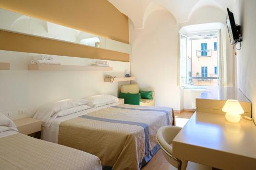 a room with two beds and a table and a window at Hotel Melograno in Spotorno