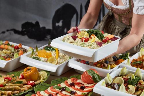 a woman holding a tray of food on a table at Sporthotel Kogler in Mittersill