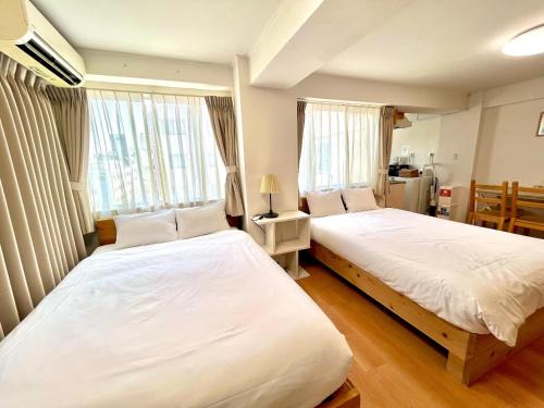 two beds in a room with two windows at Rhodes Kagurazaka in Tokyo