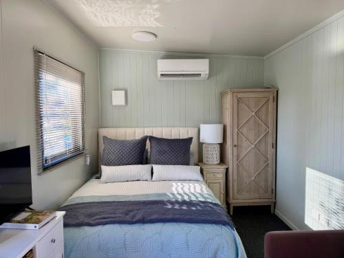 a bedroom with a bed and a dresser and a window at Benrose Stables Cottage in Palmerston North