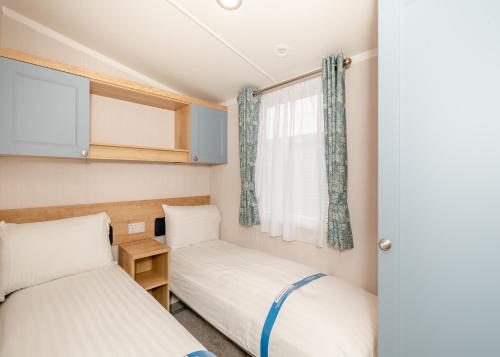 two beds in a small room with a window at Ladram Bay Holiday Park in Otterton