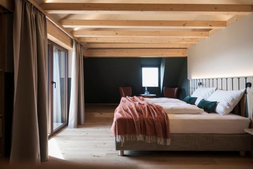 a bedroom with a large bed with a wooden ceiling at Bella Posta Hotel in Soprabolzano