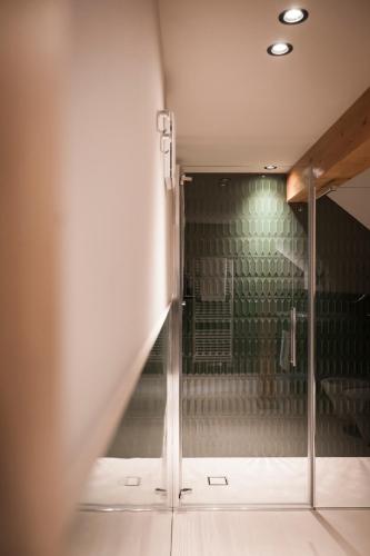 a glass shower door in a room with a wall at Bella Posta Hotel in Soprabolzano