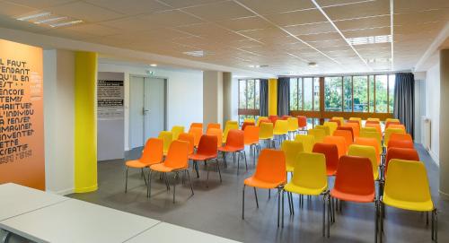 una sala de conferencias con sillas de color naranja y amarillo en Centre International de Séjour André Wogenscky, en Saint-Étienne