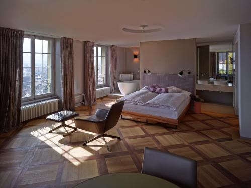 a bedroom with a bed and chairs and a bathroom at Boutique Hotel Schlossberg in Thun