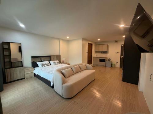 a bedroom with a bed and a couch and a television at The Sweet Escape in Ban Kathu (1)