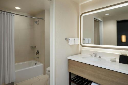 a bathroom with a sink and a tub and a mirror at Hotel Solea, Autograph Collection in Carlsbad