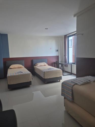 a room with three beds and a couch in it at ERCA Yogyakarta in Yogyakarta
