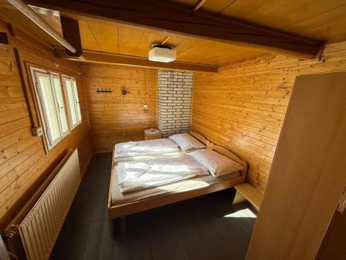 a small bedroom with a bed in a wooden room at Bouda Vlkoš in Horní Malá Úpa