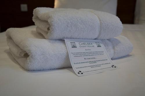 een stapel witte handdoeken zittend op een bed bij Chelsea Guest House in Londen