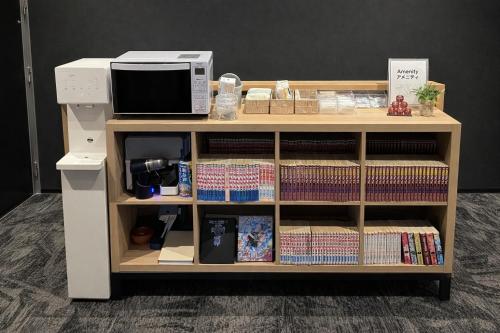 a book shelf with a microwave on top of it at My Home Inn Sennan, Onosato in Ozaki