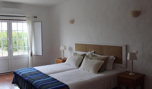 una camera con un grande letto e una finestra di Casas de Miróbriga a Santiago do Cacém