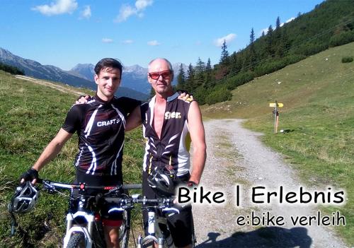 two men standing next to a bike on a dirt road at Alpenhof Wohlfühlpension in Obsteig