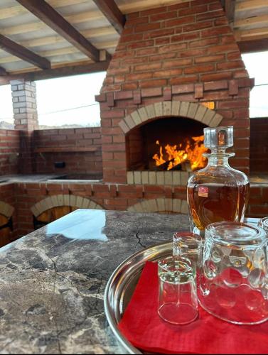 a bottle of whiskey and two glasses on a table with a fireplace at Casa Cu Lavandă in Valea Drăganului