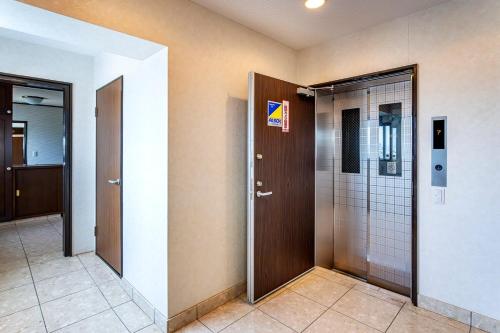 a hallway with two elevators and a door in a building at La Pace Awaji in Osaka