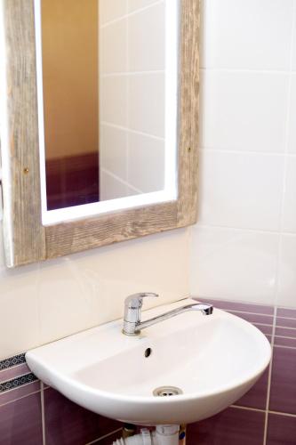 a white sink in a bathroom with a mirror at Baron Munchausen Guest House in Kamianets-Podilskyi
