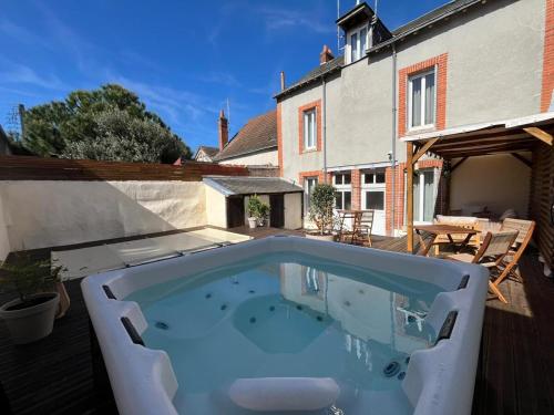 a swimming pool on a patio with a house at Maisons Sauvages - Piscine & Jacuzzi - Proche Zoo de Beauval & Châteaux in Romorantin
