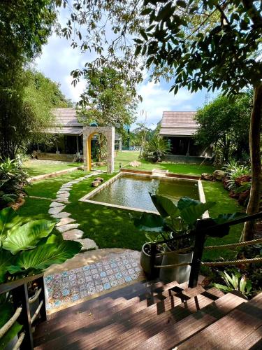 a garden with a swimming pool in a yard at El Vaso Resort in Chanthaburi