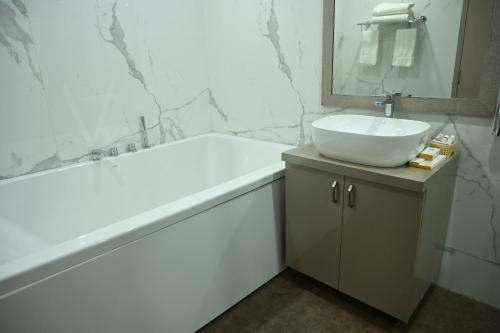 a white bathroom with a sink and a bath tub at Hotel vishnu vihar in Gaya
