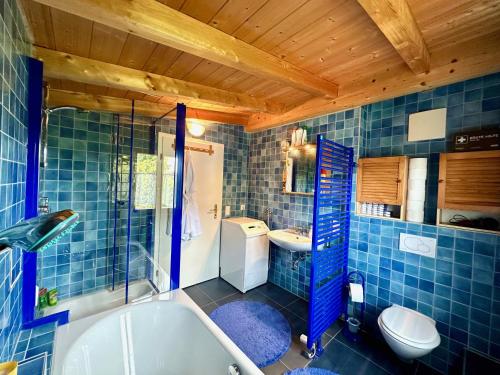 a blue tiled bathroom with a tub and a toilet at Rosi's Ferienwohnung Kampenwandblick in Prien am Chiemsee