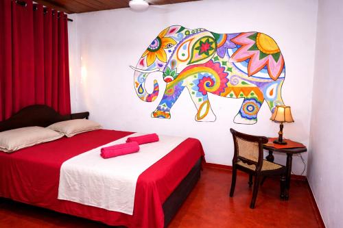 a bedroom with a bed with a painting of an elephant at Solar House Hotel in Dickwella
