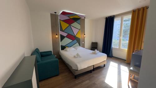 a bedroom with a bed and a green chair at Alma Hotel in Courbevoie