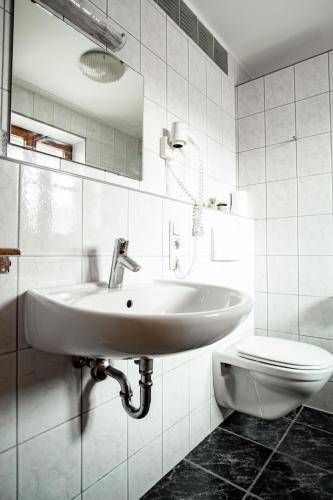 a white bathroom with a sink and a toilet at Ferienwohnungen Steinbacher in Vogtareuth