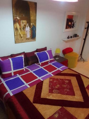a bedroom with a bed with purple and blue pillows at Tunisian style in La Marsa