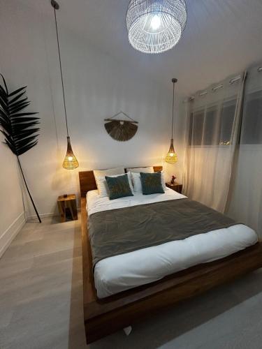 a bedroom with a large bed and two pendant lights at Charmant Appartement Grand Gosier in Le Gosier