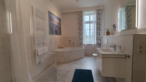a white bathroom with a tub and a sink at Ferienwohnung Fehmarn in Fehmarn